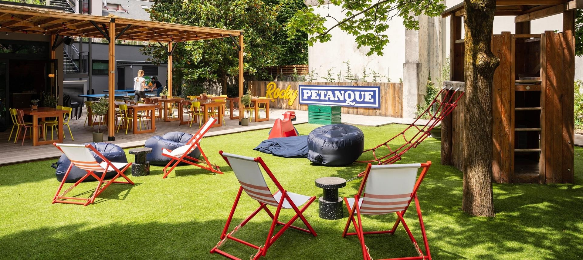 Terrasse animée du RockyPop Grenoble avec transats, terrain de pétanque et aire de jeux