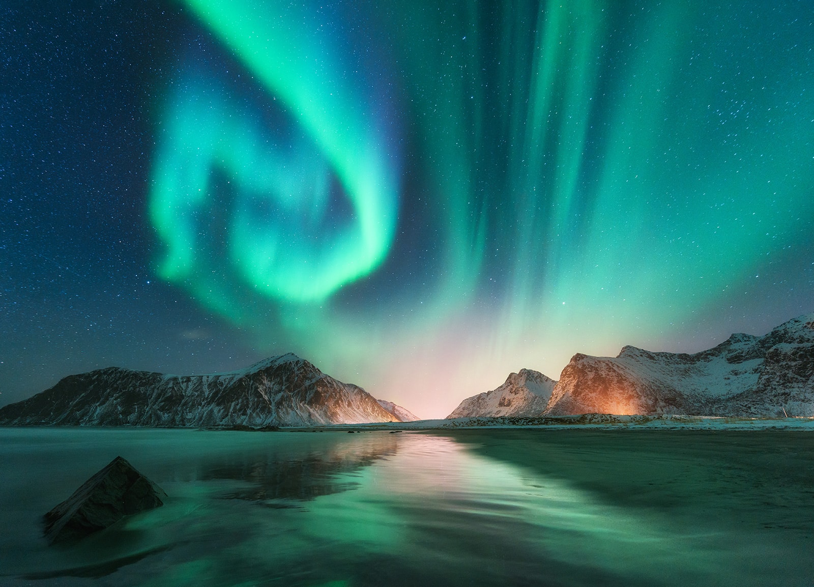 Aurores boréales dans un ciel étoilé au-dessus de montagnes enneigées