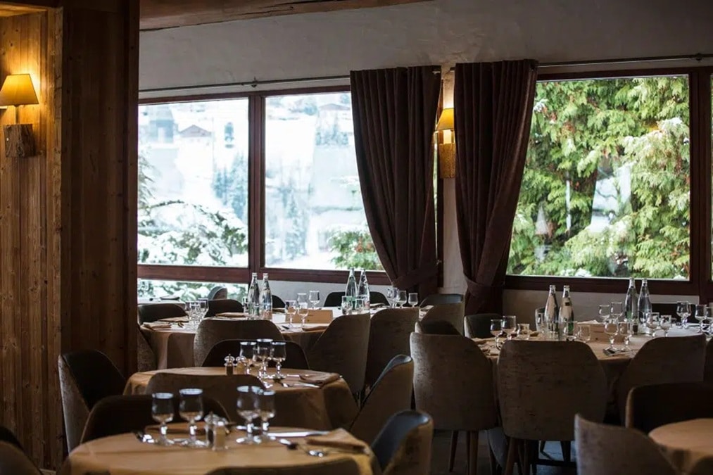 Salle de restaurant de l’hôtel Alpen Roc avec grandes fenêtres sur la nature