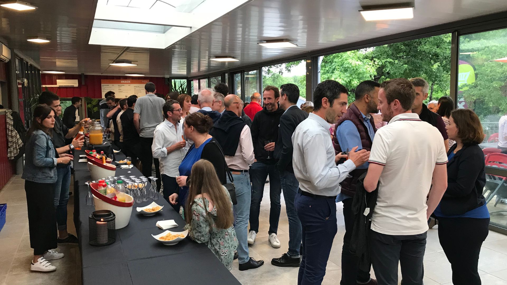 Présentation d'un Groupe de personnes en train de discuter lors d'un événement dans un hall avec un buffet.