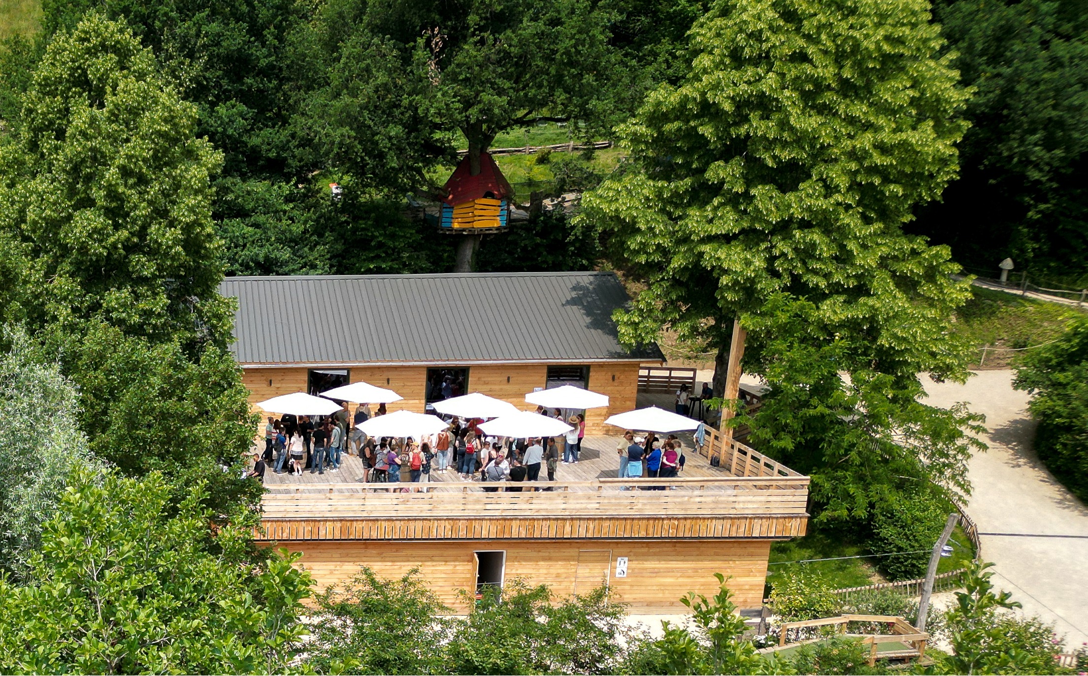 Terrasse boisée animée avec des parasols blancs et des invités réunis