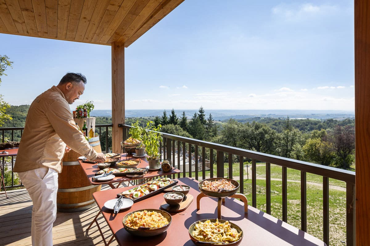 Terrasse Huttopia avec table garnie et vue panoramique sur la nature