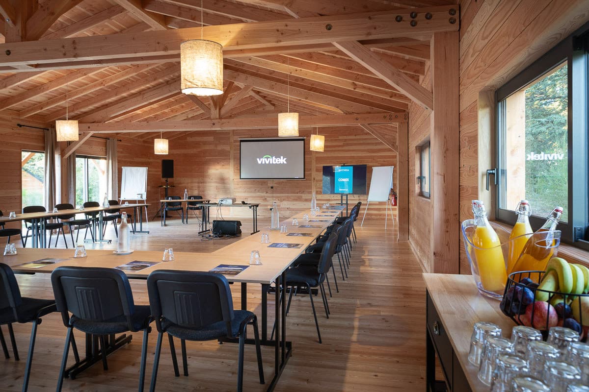 Salle de réunion Huttopia avec tables et écran de présentation
