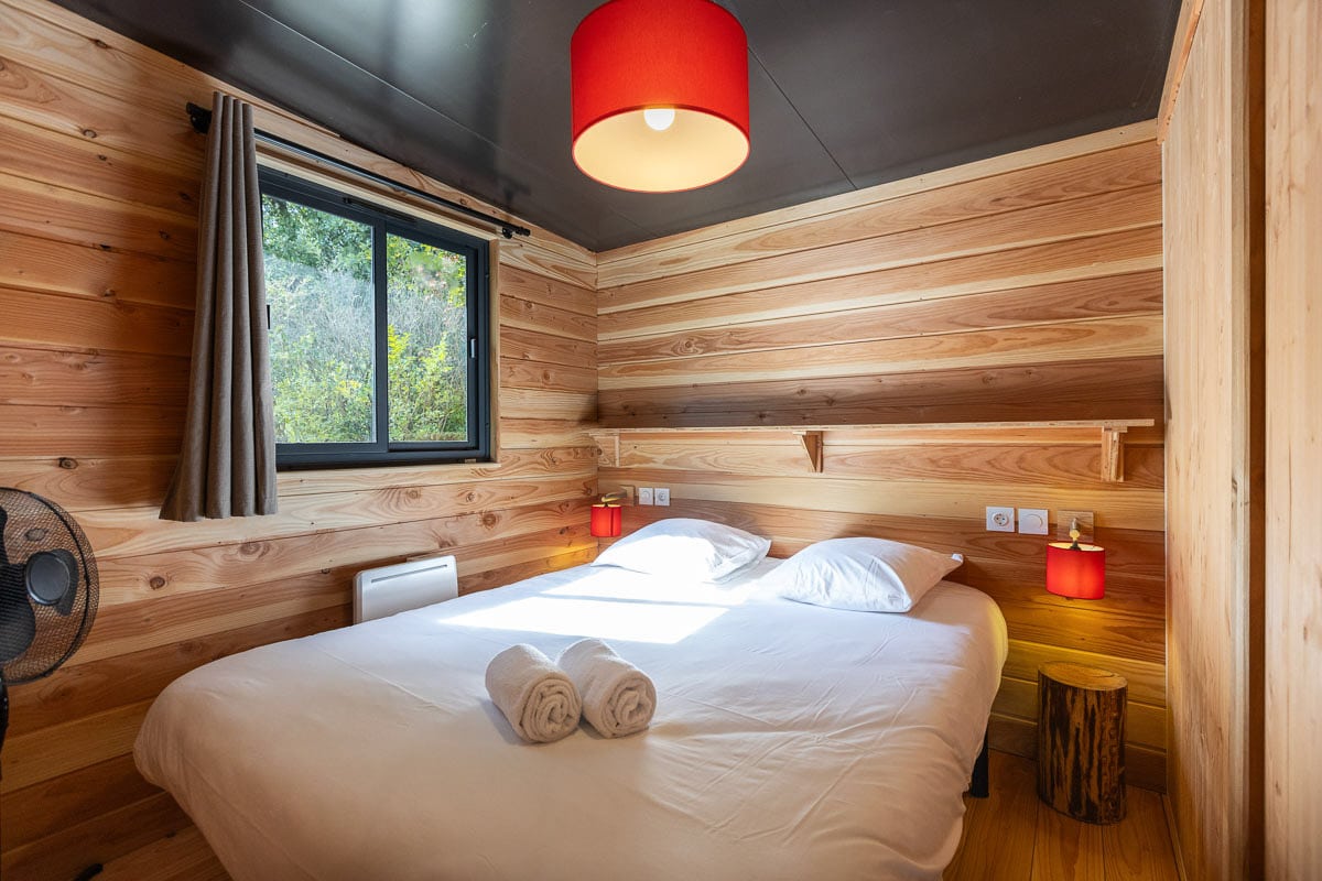 Chambre en bois Huttopia avec lit double et ambiance chaleureuse