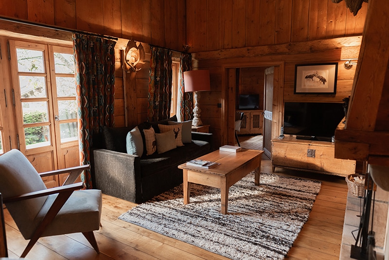 Salon en bois avec cheminée dans un chalet des Fermes de Marie