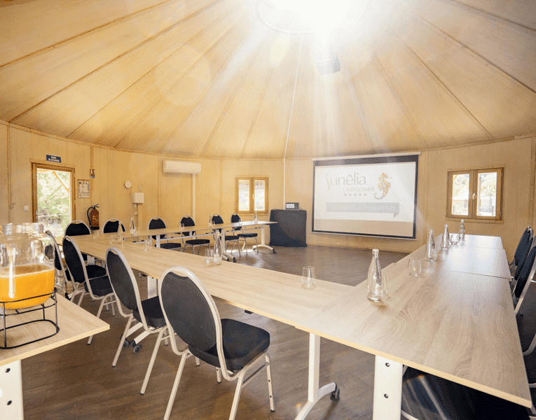 Salle de réunion équipée avec tables et chaises au Camping Sunêlia L’Hippocampe