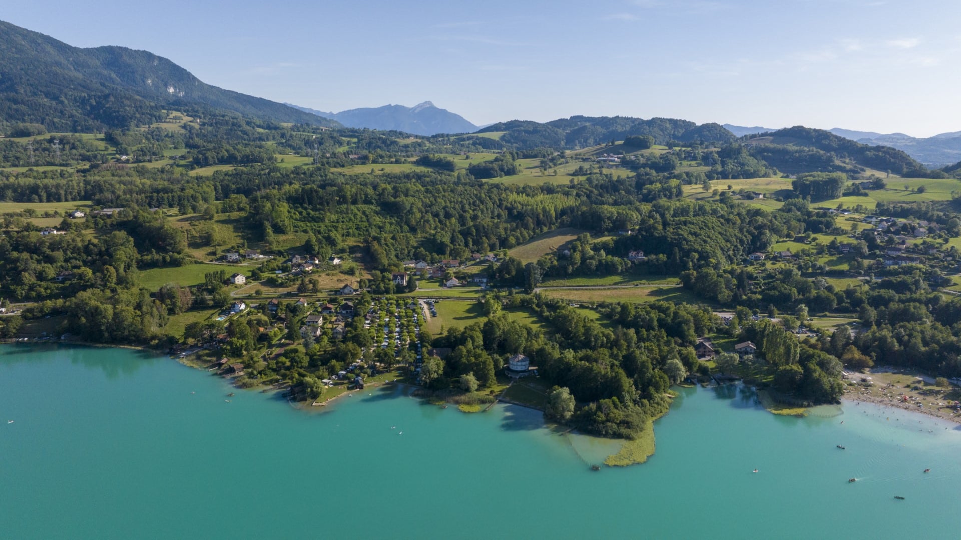 Vue aérienne du camping Huttopia Lac d’Aiguebelette entre lac et montagne en Savoie