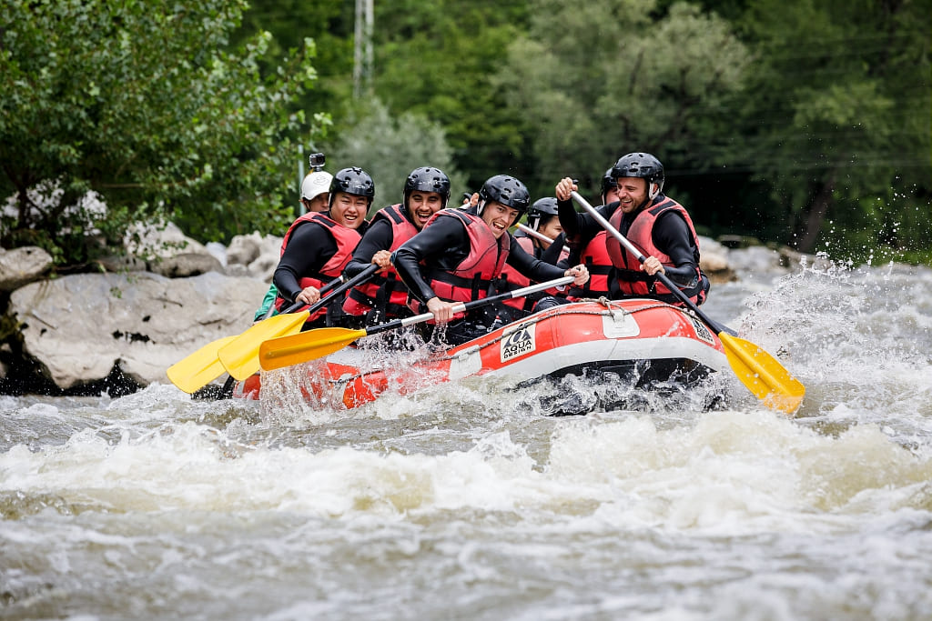 Équipe en rafting sur une rivière bordée de forêt