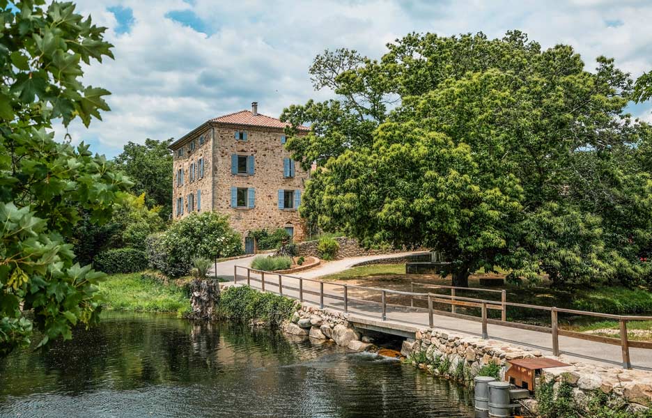 Bâtisse en pierre du Domaine des Ranchisses bordée par la rivière en Ardèche