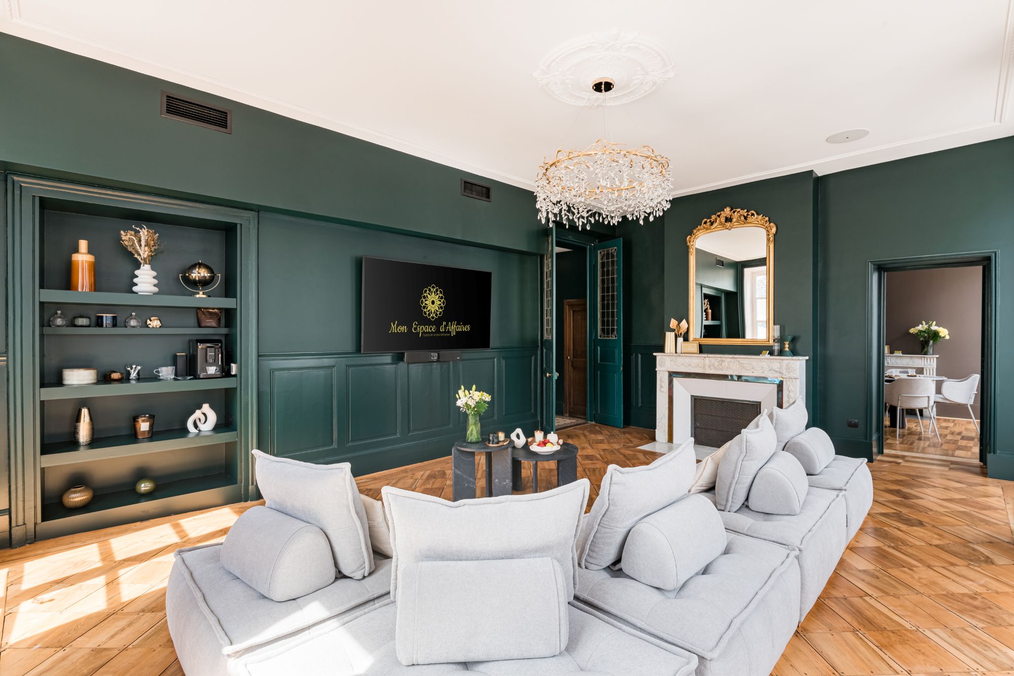 Salon avec TV murale et canapés clairs dans un cadre raffiné