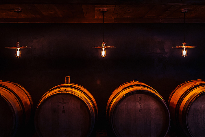 Caveau voûté avec fûts en bois et lumière tamisée – Les Larmes du Soleil