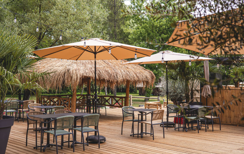 Terrasse ombragée avec tables et parasols aux Lodges du Lac