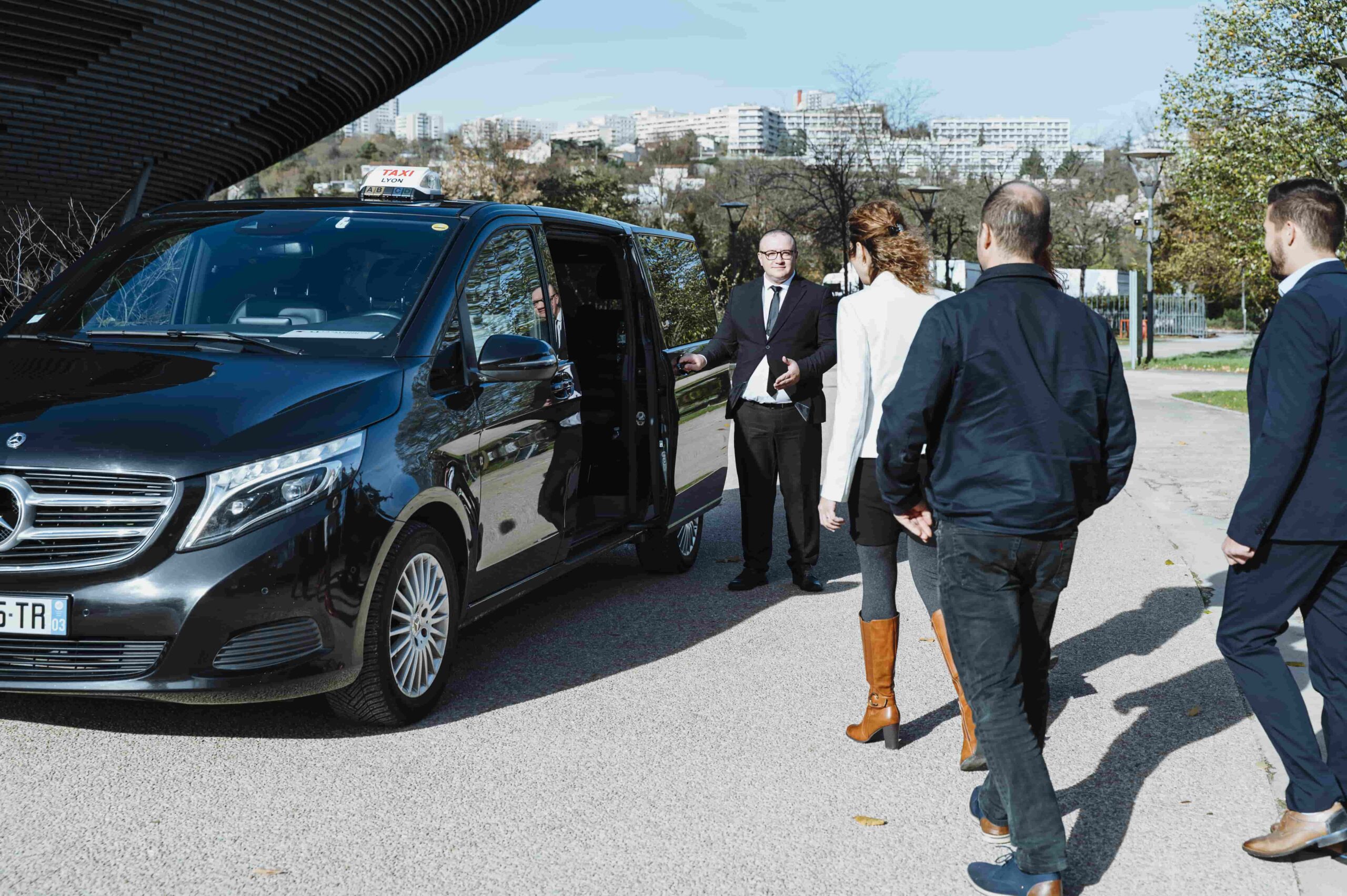 Chauffeur GTL accueillant des participants devant un van premium