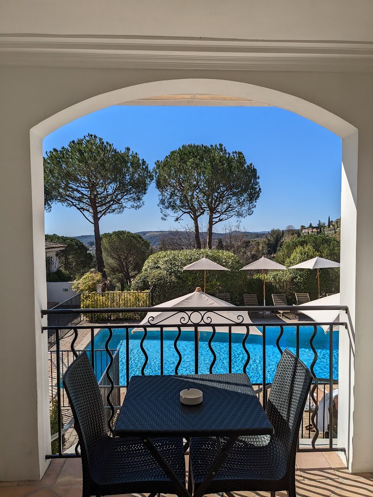 Vue depuis une terrasse avec piscine et pins en arrière-plan