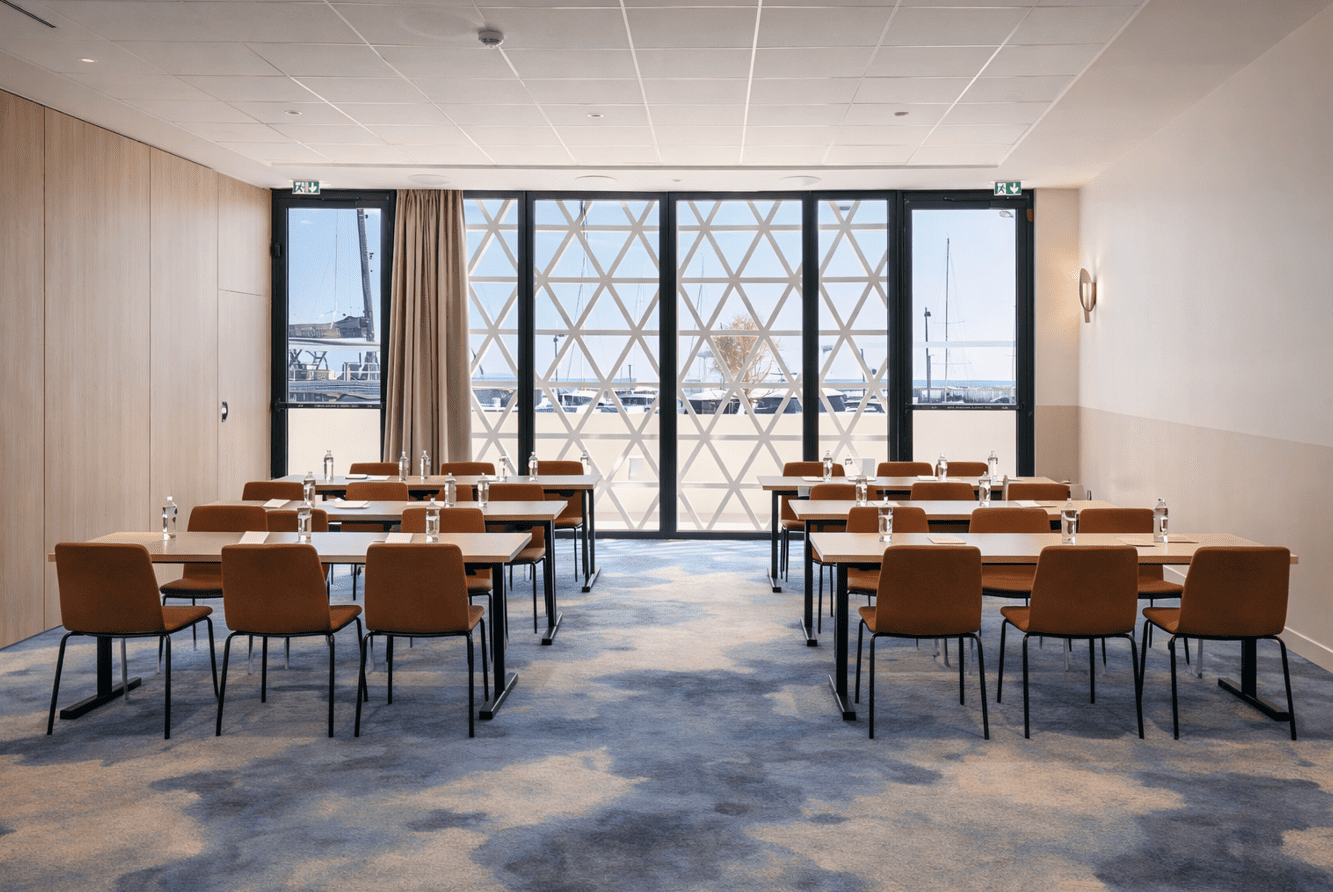 Salle de conférence lumineuse avec tables et grandes fenêtres à Marina Baie des Anges