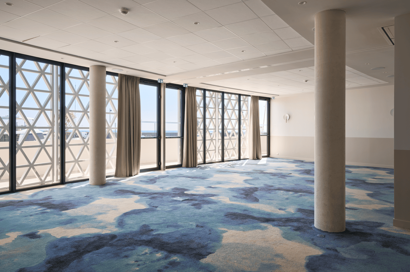 Grande salle événementielle vide avec moquette design à Marina Baie des Anges