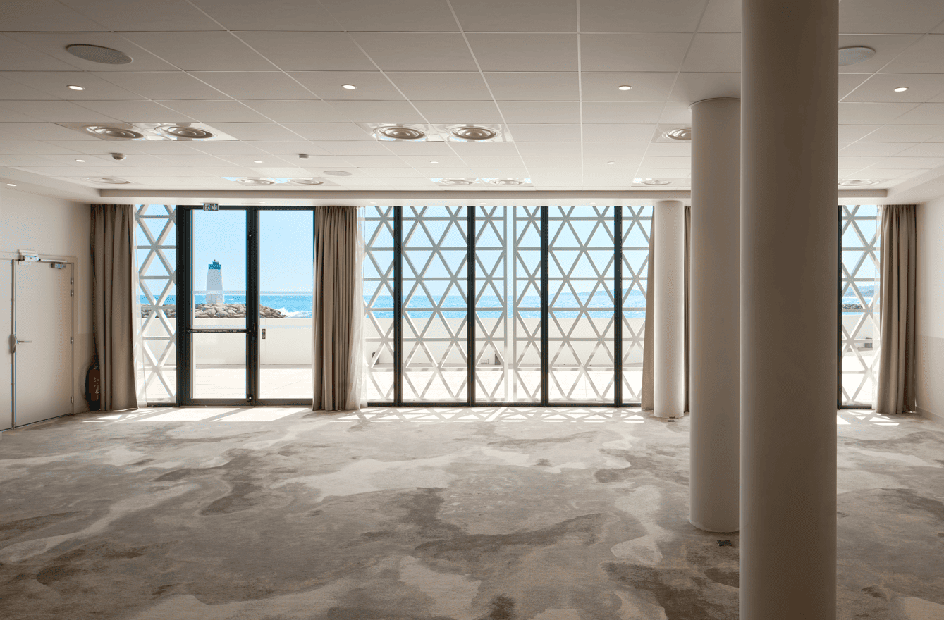 Salle de réception vide avec grandes baies vitrées à Marina Baie des Anges